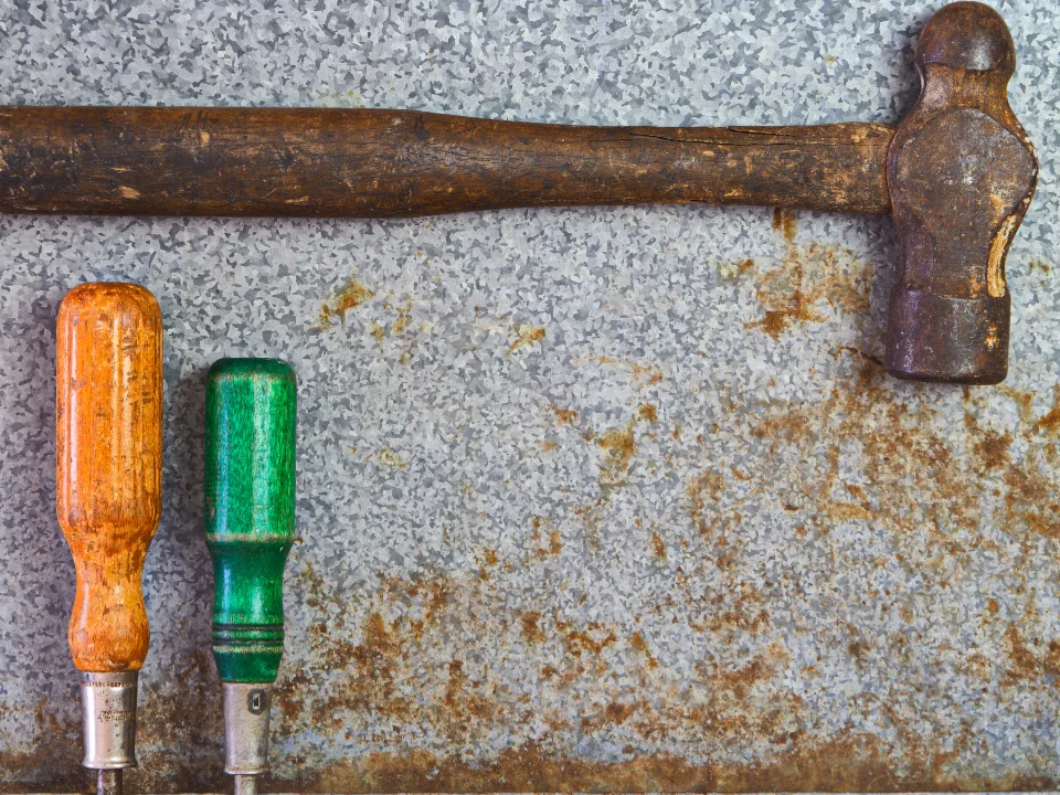 Hammer and screwdrivers on a weathered metal surface